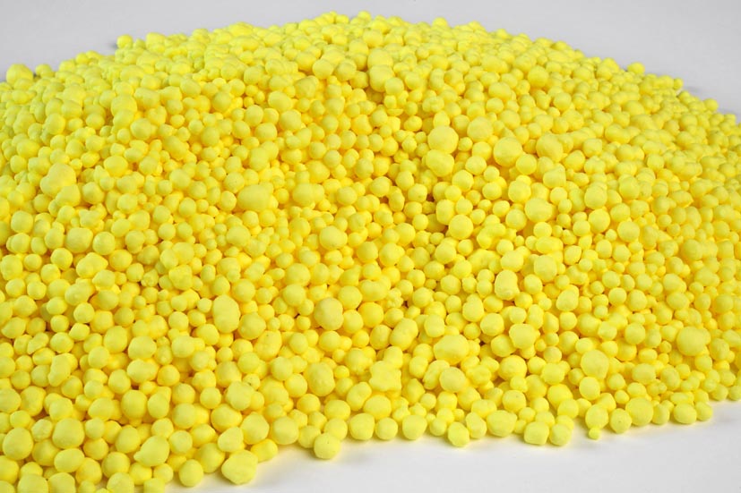 Bright yellow granular sulfur piled on a white surface