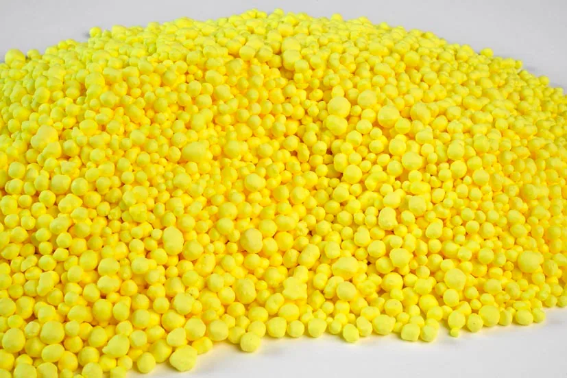 Bright yellow granular sulfur piled on a white surface
